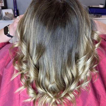 A deep brunette base melting down into blonde ends, curled at the bottom and seen from behind.