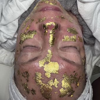 Sheets of gold leaf laid in patches across the face, over a towel wrap.